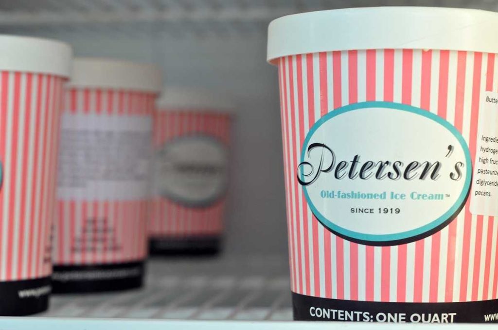 Pink and white striped Petersen's one-quart ice cream tubs on a freezer shelf.